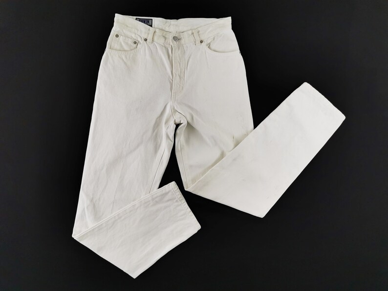 May include: Off-white denim jeans with a classic five-pocket design. The jeans have a button and zipper closure, belt loops, and a straight leg fit. The garment is made of a sturdy cotton blend and is suitable for casual wear.