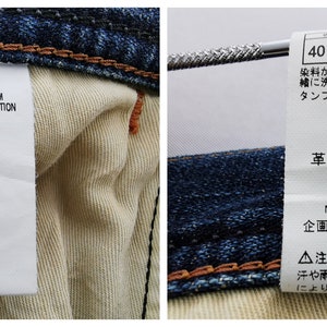 Może przedstawiać: Zbliżenie dw&oacute;ch metek przymocowanych do pary niebieskich dżins&oacute;w. Jedna metka wyświetla "Wrangler" i rozmiar "30". Druga zawiera instrukcje prania i skład materiału: 100% bawełna, sk&oacute;ra syntetyczna.