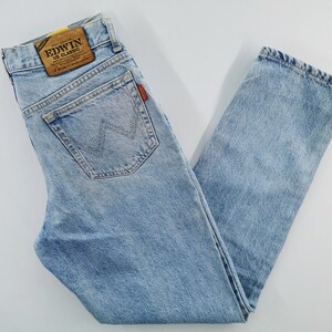 May include: Light blue denim jeans with a classic straight-leg fit. Features a back pocket with a stitched design and a leather patch with the brand name. The jeans have a faded wash and a vintage look.