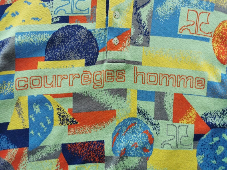 May include: A polo shirt with a colorful geometric pattern in shades of blue, yellow, orange, and gray. The shirt features the text "courr&egrave;ges homme" in orange. The shirt has a collared neckline and two white buttons.