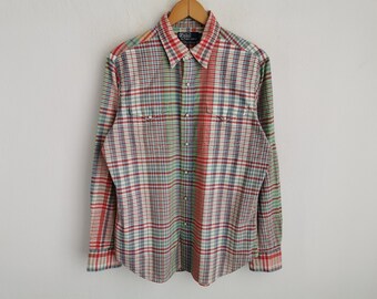 Puede incluir: Una camisa de manga larga con botones y un patrón de cuadros multicolor en rojo, verde, azul y blanco. La camisa incluye un cuello puntiagudo, dos bolsillos en el pecho con solapas y una etiqueta Polo by Ralph Lauren en el cuello.