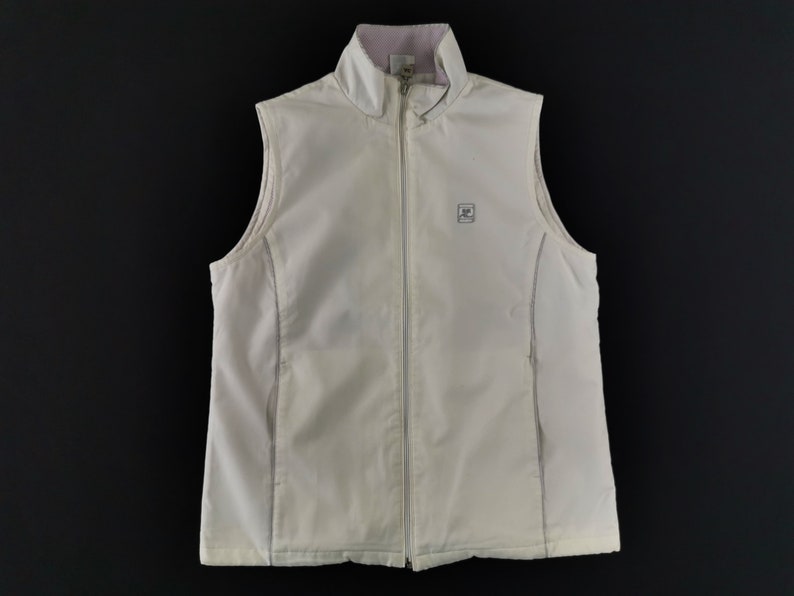 Puede incluir: Un chaleco sin mangas de color crema con cremallera completa y un peque&ntilde;o logotipo en el pecho. El chaleco tiene un cuello alto con interior rosa claro. El chaleco est&aacute; hecho de un material suave y ligero.