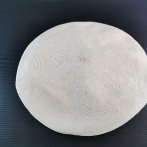 Puede incluir: Un sombrero boina beige con un dise&ntilde;o circular. El sombrero est&aacute; hecho de un material tejido y tiene una corona plana y redonda. La boina es un estilo cl&aacute;sico, adecuado para diversas ocasiones.