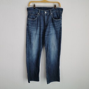 May include: Blue denim jeans hanging on a wooden hanger. The jeans have a classic five-pocket design, a button and zip closure, and a medium wash. The denim trousers are a straight-leg style.