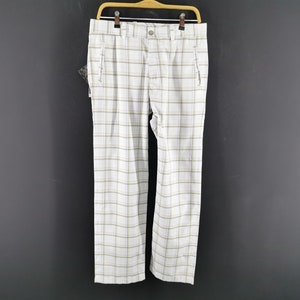 Op de afbeelding: Witte en gele geruite broek met een riemlus en twee voorzakken.