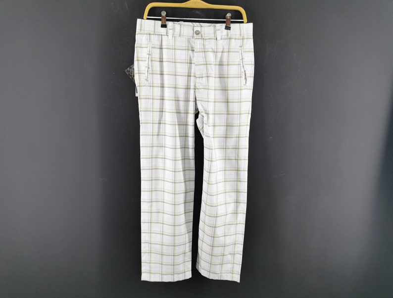 Op de afbeelding: Witte en gele geruite broek met een riemlus en twee voorzakken.