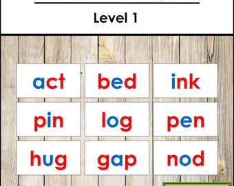Op de afbeelding: Negen witte kaarten met rode en blauwe letters die de woorden act, bed, ink, pin, log, pen, hug, gap en nod spellen. De kaarten zijn gerangschikt in drie rijen van drie kaarten. De kaarten bevinden zich op een houten achtergrond. De tekst "Phonetic Word Cards Level 1" staat bovenaan de afbeelding. De tekst "Montessori Print Shop" staat onderaan de afbeelding.