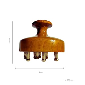 May include: A wooden head massager with a rounded handle and a flat base featuring several metal prongs. The massager is 6.5 cm tall and 8 cm wide. The weight is 140 grams.