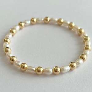 May include: A gold and white pearl bracelet with alternating gold beads and white pearls.