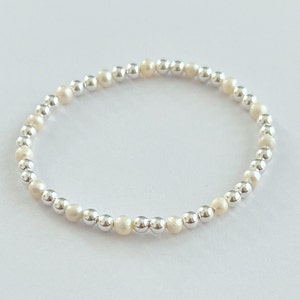 May include: A silver and white beaded bracelet with alternating silver and white beads.