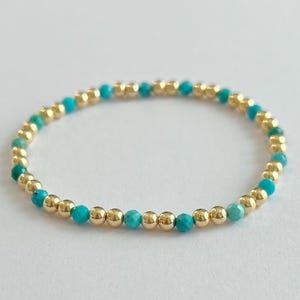 May include: A gold and turquoise beaded bracelet. The bracelet is made with small, round gold beads and turquoise beads.