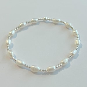 May include: A delicate bracelet made with small white pearls and silver beads.