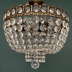 May include: An ornate chandelier featuring a brass frame and a multitude of clear crystal embellishments. The crystals are arranged in layers, creating a cascading effect. The chandelier is suspended from the ceiling and is designed to illuminate a room.