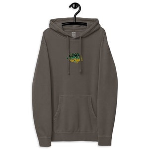 Op de afbeelding: Een donkergrijze hoodie met een klein geborduurd beeld van een groene en gele kikker op de voorkant.