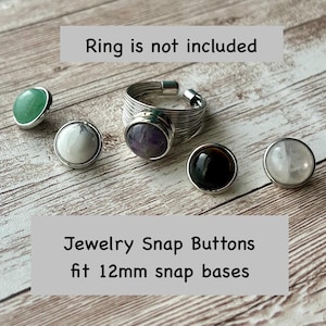 K&ouml;nnte beinhalten: Schmuck-Druckkn&ouml;pfe mit verschiedenen Edelstein-Designs, darunter gr&uuml;ne, wei&szlig;e, schwarze und violette Steine. Das Bild zeigt auch einen silbernen Drahtring. Der Text auf dem Bild lautet: "Ring is not included" und "Jewelry Snap Buttons fit 12mm snap bases."
