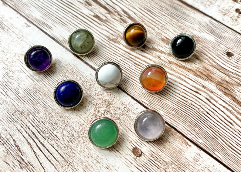 May include: Individual round gemstone cabochons in various colors, including amethyst, lapis lazuli, tiger's eye, black onyx, white howlite, carnelian, rose quartz, and green aventurine. The stones are set in silver-toned bezels. Individual snap buttons fit 12mm snap bases.