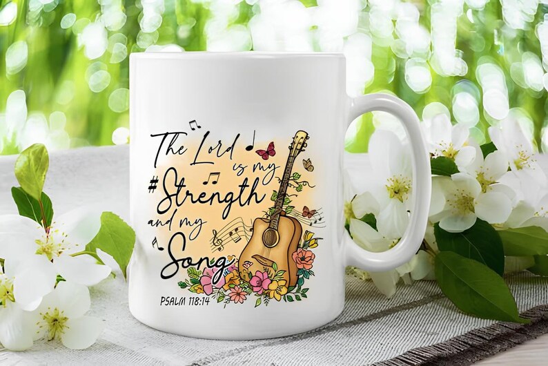 K&ouml;nnte beinhalten: Wei&szlig;e Keramiktasse mit einem farbenfrohen Design mit einer Gitarre, Blumen, Noten und dem Text "The Lord is my Strength and my Song, Psalm 118:14".