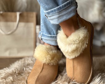 Puede incluir: Zapatillas de ante color canela con ribete de borrego color crema. Las zapatillas se llevan con vaqueros azules. Las zapatillas están sobre una alfombra cremosa y esponjosa. Costura cosida en el borde.