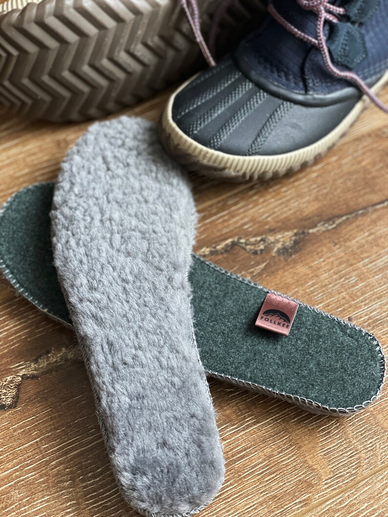 May include: A pair of gray fleece insoles with a green felt insole with the word "Follea" on a brown leather tag.