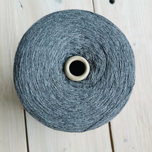 May include: A spool of dark grey yarn wound around a cardboard centre.