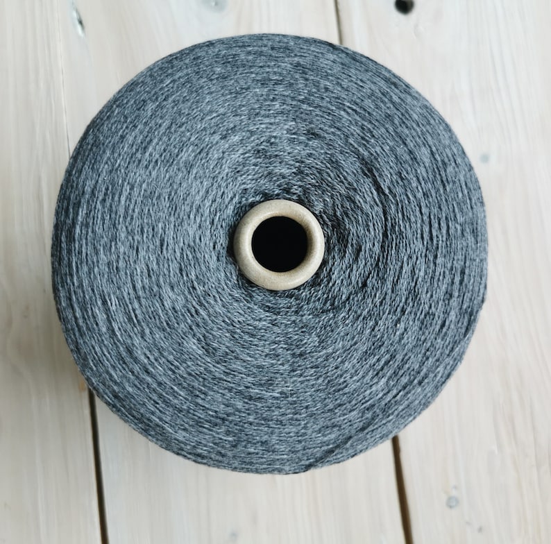 May include: A spool of dark grey yarn wound around a cardboard centre.