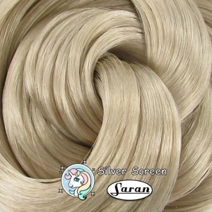 May include: A close-up of a bundle of light beige saran wrap. The wrap is twisted and folded, showing its texture. The text "Silver Screen" and the Saran brand logo are visible in the lower right corner.