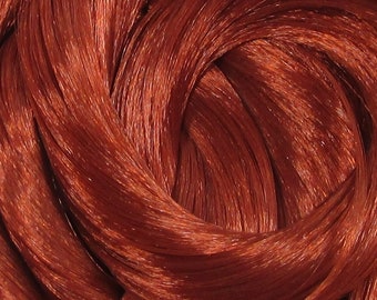 May include: Close-up of a bundle of bright red hair extensions. The strands are smooth and shiny, creating a luxurious look.