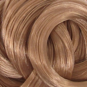 May include: Close-up of a bundle of light brown human hair extensions. The hair is smooth and shiny, with a slight reddish tint.