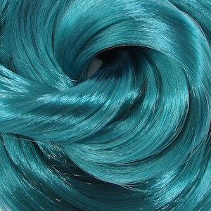May include: A close-up of teal blue yarn, showing the texture and shine of the fibers.