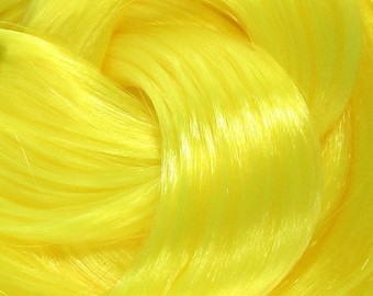 May include: Close-up of bright yellow synthetic hair fibers. The fibers are soft and shiny, with a smooth texture.