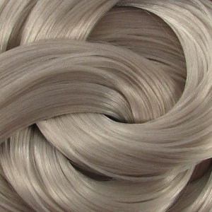 May include: Close-up of a silver-grey hair extension. The hair is smooth and silky, with a slight sheen.