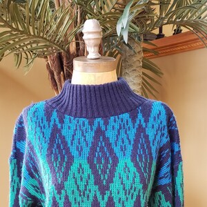 May include: A blue, green, and black patterned sweater with a high neck.