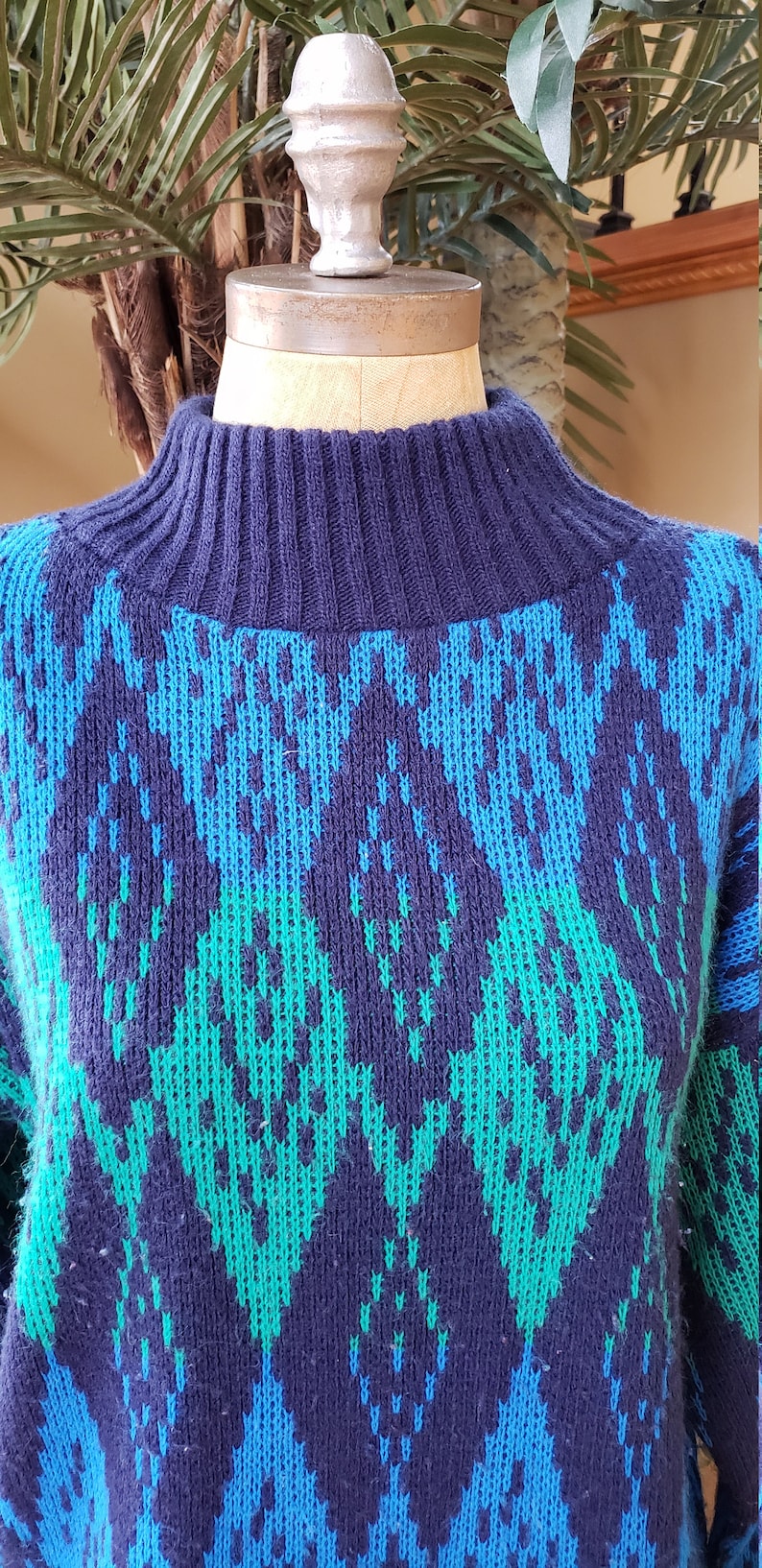 May include: A blue, green, and black patterned sweater with a high neck.