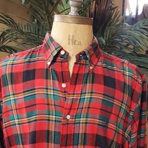 May include: A red, green, black, and yellow plaid long-sleeved button-down shirt.