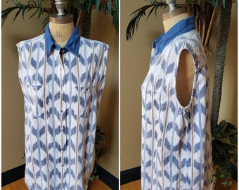 Puede incluir: Una camisa blanca sin mangas con botones y un patrón geométrico azul y marrón. La camisa tiene un cuello de mezclilla y dos bolsillos en el pecho.