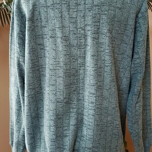 May include: A green long-sleeved sweater with a textured pattern. The sweater is on a mannequin.