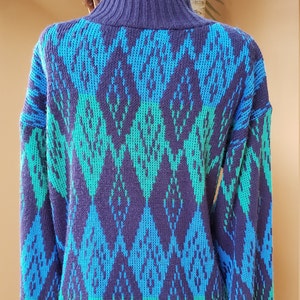 May include: A blue and green patterned sweater with a high neck. The sweater is made of a soft, knitted fabric.