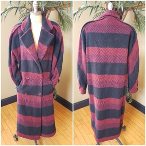 May include: A long, black and burgundy striped wool coat with a double breasted closure and pockets. The coat has a classic, tailored silhouette.