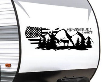 May include: Black and white decal featuring a stylized American flag, mountains, a deer, and the text "Adventure Awaits". The decal is applied to the side of a white camper.