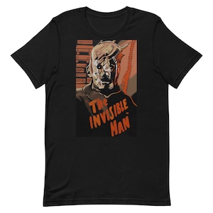Puede incluir: Camiseta negra con una ilustración de estilo vintage de un hombre con la cara vendada. El texto "The Invisible Man" está impreso en naranja debajo de la ilustración.