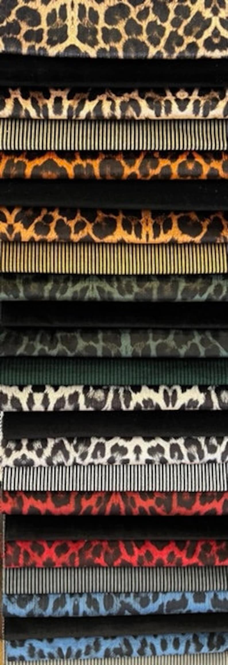 May include: A stack of fabric swatches with various animal print patterns, including leopard, zebra, and cheetah. The swatches are arranged in a vertical stack, with the top swatch being a leopard print and the bottom swatch being a blue and white striped pattern.
