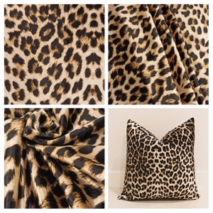 May include: Close-up of a brown and black leopard print fabric. The fabric is soft and plush, with a subtle sheen. The print is realistic and detailed, with a variety of spot sizes and shapes.
