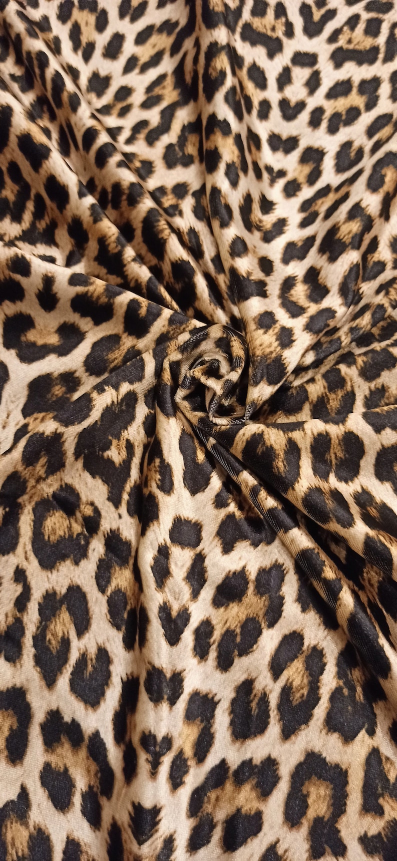 May include: Close-up of a brown and black leopard print fabric. The fabric is soft and has a subtle sheen.