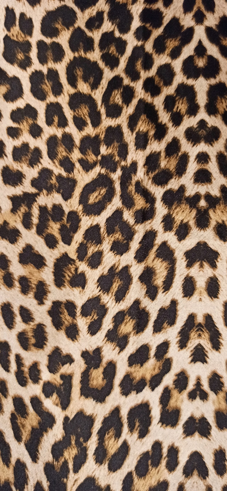 May include: A close-up of a brown and black leopard print fabric. The fabric has a soft, fuzzy texture.