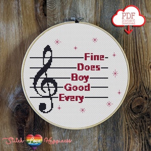 May include: Cross stitch pattern featuring a treble clef and the lyrics "Fine Does Boy Good Every". The pattern is displayed in a white embroidery hoop with a wooden frame.