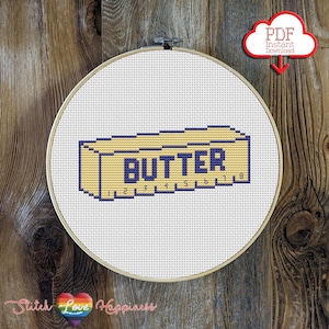 May include: A cross-stitch embroidery hoop featuring a yellow and blue design of a butter stick with the word "BUTTER" in blue. The design includes measurement markings. A red cloud graphic with "PDF Instant Download" is in the upper right.