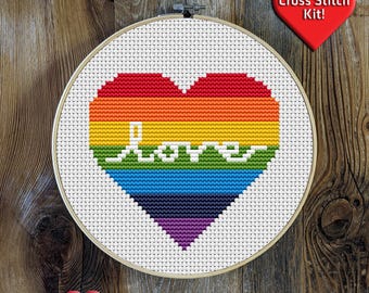 May include: Cross stitch kit featuring a rainbow heart with the word "love" in white lettering. The heart is in a wooden embroidery hoop.