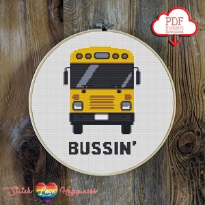 May include: A cross-stitch pattern featuring a yellow school bus with the text "Bussin'" underneath. The pattern is displayed in a white embroidery hoop.