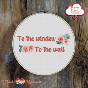 Puede incluir: Patrón de punto de cruz con la frase "To the window, To the wall" con flores rosas sobre un fondo blanco. El patrón está en un aro y listo para ser cosido.