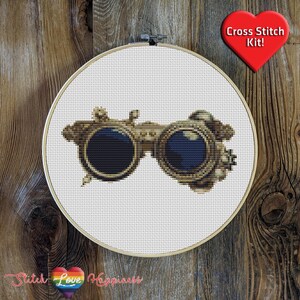 May include: Cross stitch pattern kit featuring a pair of vintage steampunk goggles with gold accents and blue lenses.